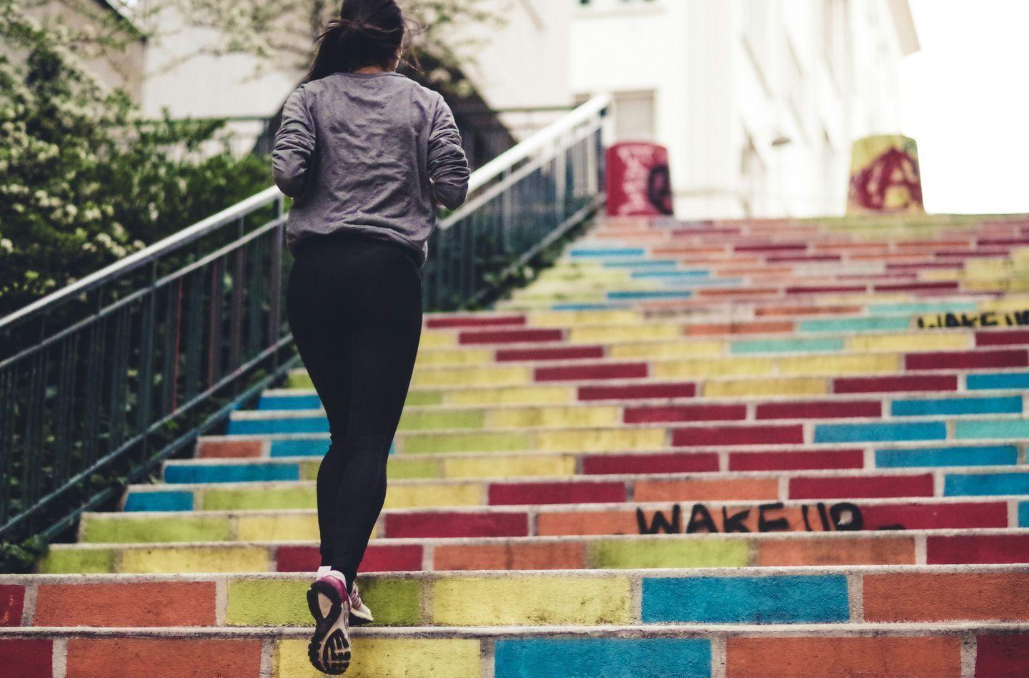 Person running up colorful stairs representing step-by-step progress